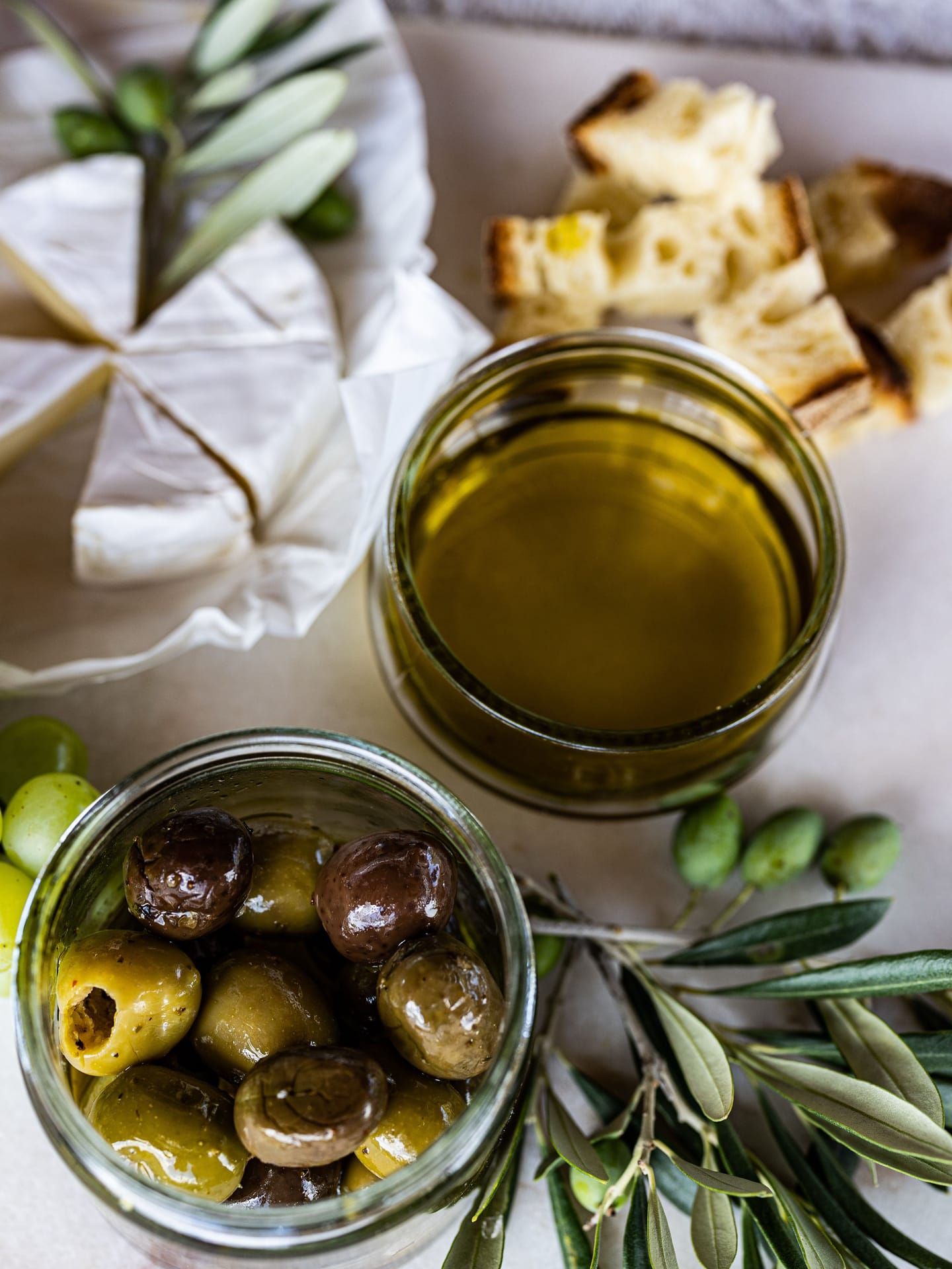 Olive, olio extravergine d'oliva, pane e formaggio con rami d'ulivo — la convivialità attorno all'olio di Canino